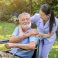 Happy nurse holding elderly man hand on wheelchair in garden at nursing home